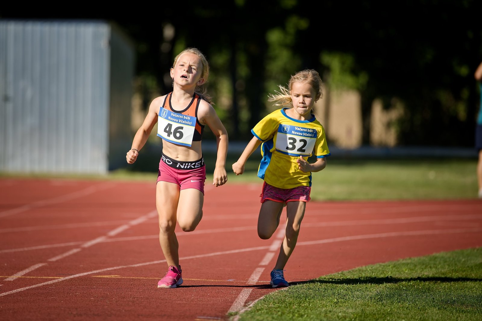 Dvě mladé běžkyně závodí na atletické dráze